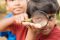 Elementary age boy uses magnifying glass to discover nature.   This curious, student explorer excitedly investigates an insect, which he holds in his hand. His friend is in the background. The children are of Asian, Indian, Latin descent.  Science, education themes.